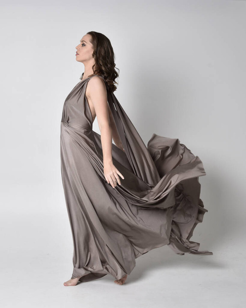 Портрет красивої брюнетки в довгій срібній вечірній сукні, повнометражна позу на фоні студії
 - Фото, зображення