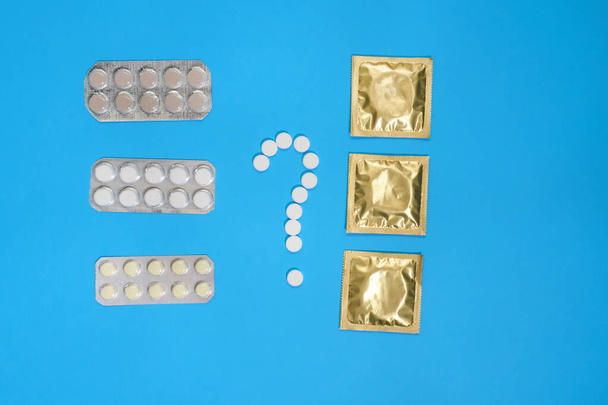 Anticonceptiepillen en condooms op een blauwe achtergrond. Zicht van bovenaf. Begrip anticonceptie. medisch concept, Vlakke vloer - Foto, afbeelding