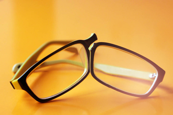 Σπασμένα κίτρινα γυαλιά σε πορτοκαλί φόντο τόσο κοντά - Φωτογραφία, εικόνα
