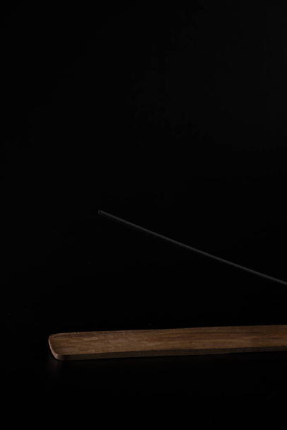 Incense on a beautiful wooden stand, on a black background. Aromatherapy for health and prosperity. The concept of meditation, zen and self-knowledge - 写真・画像