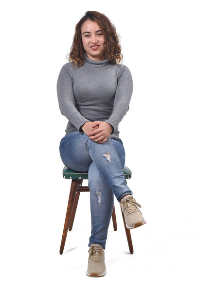 portrait of a woman sitting on a chair in white background, looking at camera and legs crossed - Fotoğraf, Görsel