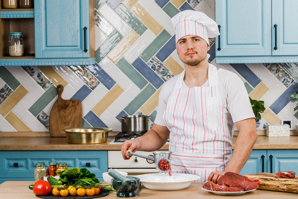 Syrové maso. Příprava mletého masa se provádí pomocí mlýnku na maso. Šéfkuchař používá mlýnek na maso v kuchyni. - Fotografie, Obrázek