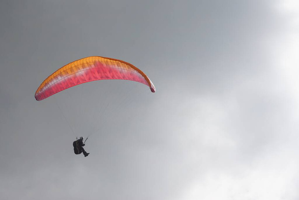 A paraglider in the sky against gray cloudy background - Фото, зображення