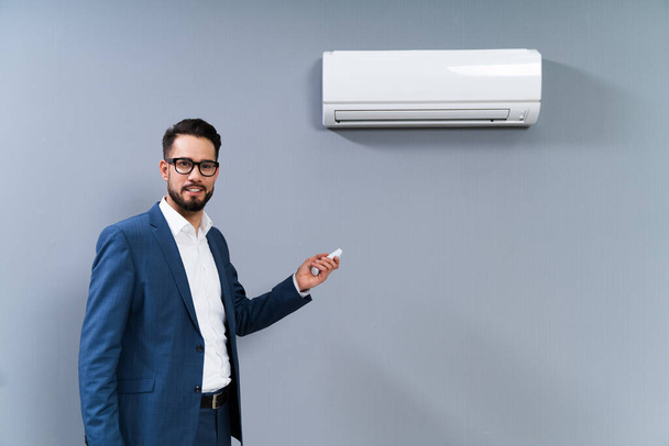 Portrait Of A Man Operating Air Conditioner With Remote Controller - Foto, Imagen