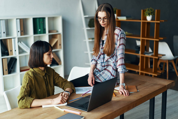 Две серьезные деловые женщины на встрече с помощью ноутбука в минималистском офисе
 - Фото, изображение