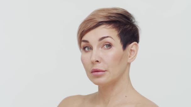 Close-up of middle aged mature woman over white bacjground. Portrait of mature lady. Plastic surgery, beauty injections, cosmetology concept. - Footage, Video