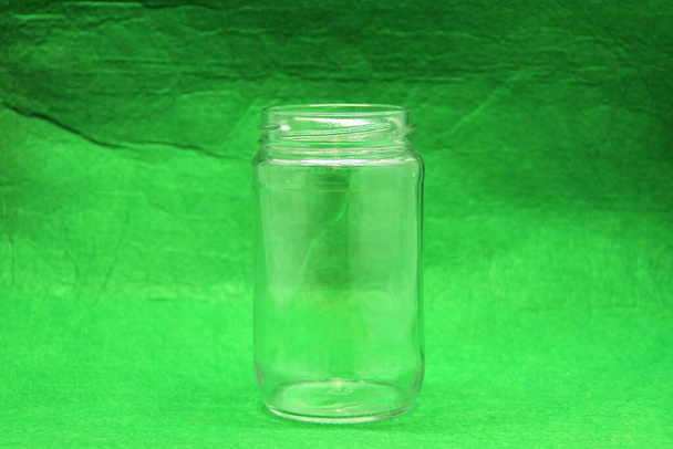 Glass empty bottle on green background, side view. Stock photo with empty space for text and design. - Fotoğraf, Görsel