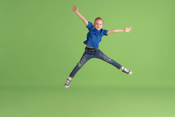 Happy boy playing and having fun on green studio background, emotions - Фото, зображення