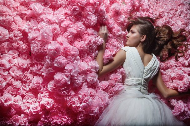 Beautiful female in white wedding dress in pink paper flowers - Photo, image