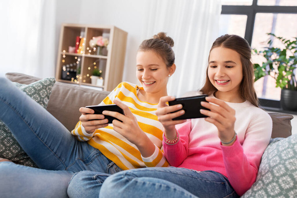happy teenage girls with smartphones at home - 写真・画像