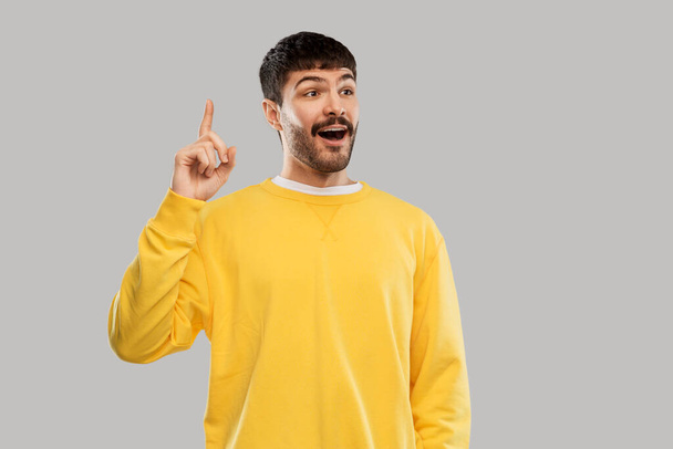 young man showing one finger in yellow sweatshirt - Fotografie, Obrázek