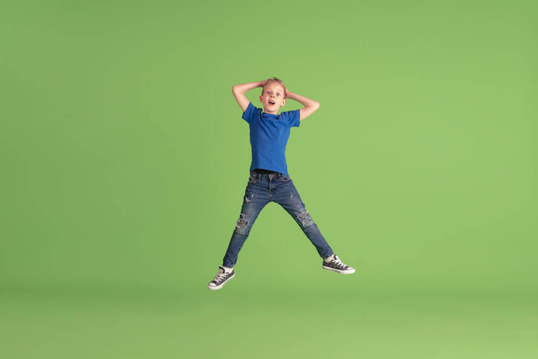 Happy boy playing and having fun on green studio background, emotions - Photo, image