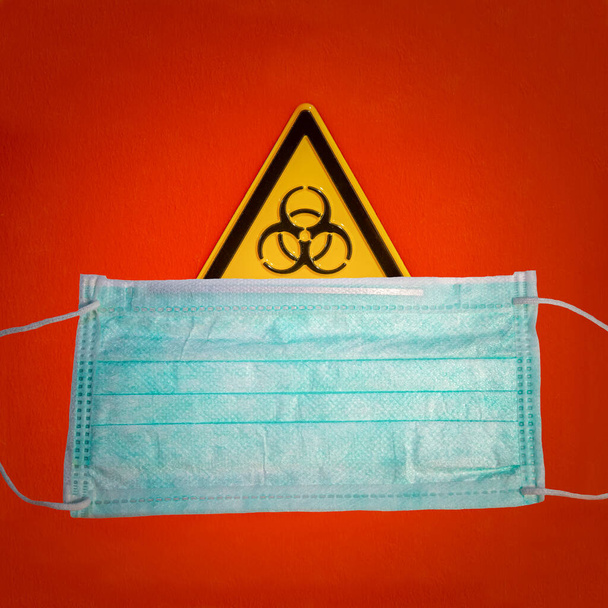 Door sign of biohazard, dangerous contamination as viral, bacterial or fungi, and a medical face mask - Photo, Image
