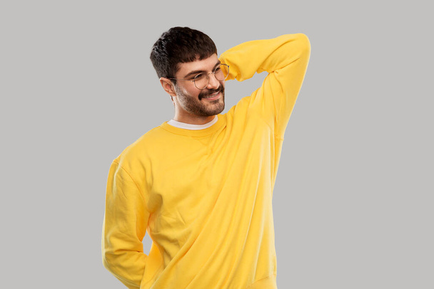 smiling young man in glasses and yellow sweatshirt - Фото, изображение