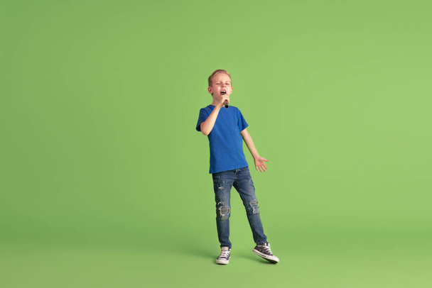 Happy boy playing and having fun on green studio background, emotions - 写真・画像