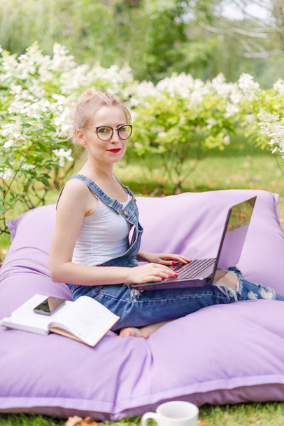 Freelancer working in the garden. Writing, surfing in the internet. Young woman relaxing and having fun in park area. Distance education, freelance concept. - Zdjęcie, obraz