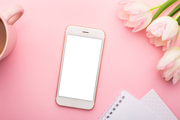 Mobile phone, notebook and spring flower pink tulips on the pink background. Theme of love, mother's day, women's day flat lay top view - Foto, Imagen