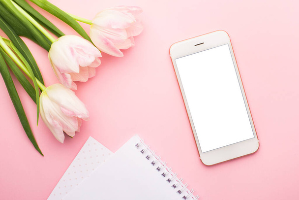 Mobile phone, notebook and spring flower pink tulips on the pink background. Theme of love, mother's day, women's day flat lay top view - Foto, immagini