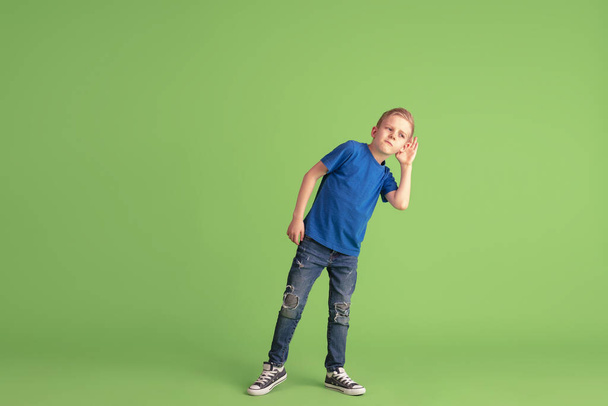 Happy boy playing and having fun on green studio background, emotions - Foto, afbeelding