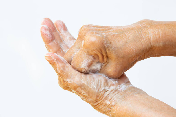 Üst düzey kadının elleri, beyaz arka planda sabun köpüğü kullanarak ellerini yıkıyor, & Macro çekimini kapat, Seçici odak, Covid19, Bakteri, Sağlık Konsepti, 7 adım el yıkama - Fotoğraf, Görsel