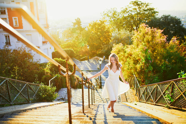 Beautiful young woman in white dress walking on famous Montmartre hill in Paris, France at early morning - Φωτογραφία, εικόνα