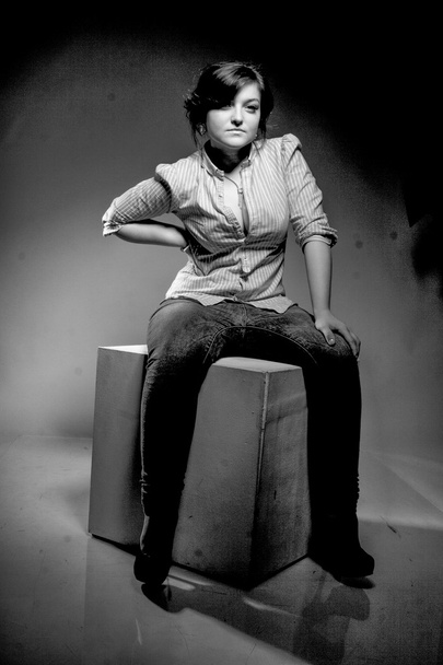 ホワイト キューブの上に座ってジーンズでセクシーな女性の肖像画 - 写真・画像