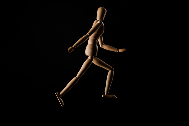 Wooden doll imitating running isolated on black  - Foto, afbeelding