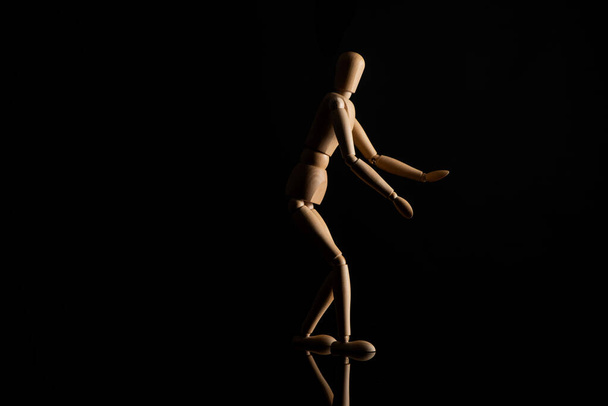 Wooden doll with outstretched hands on black background - Foto, Bild