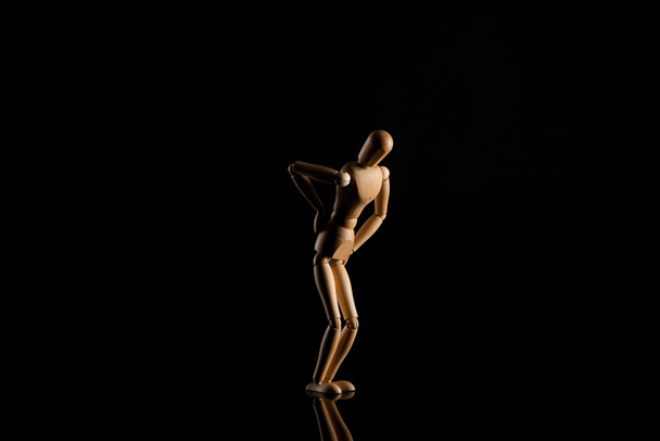 Wooden doll imitating backache on black  - Foto, Imagem