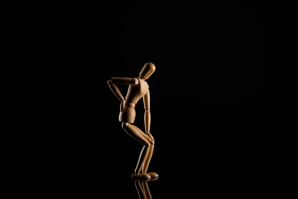 Wooden doll imitating backache on black background - Photo, Image