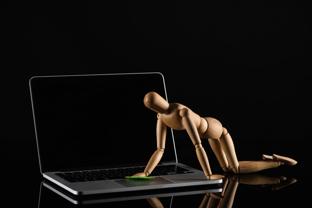 Bambola in legno su tutte e quattro le posizioni imitando spolverare laptop su sfondo nero
 - Foto, immagini