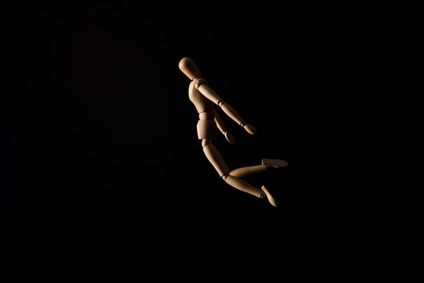 Dřevěná panenka v pádu pozici na černém pozadí - Fotografie, Obrázek