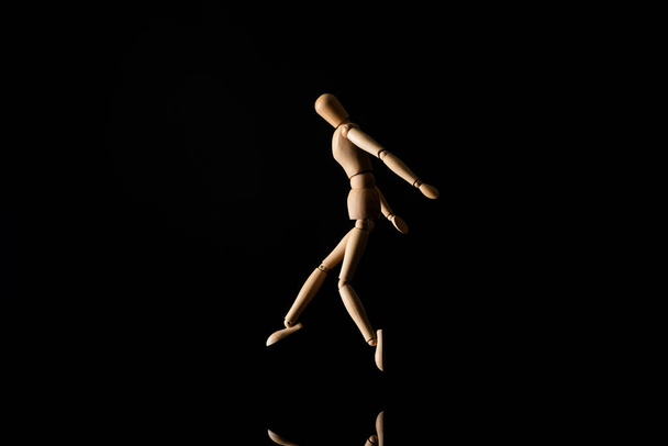 Wooden doll imitating jumping on black  - Foto, Bild