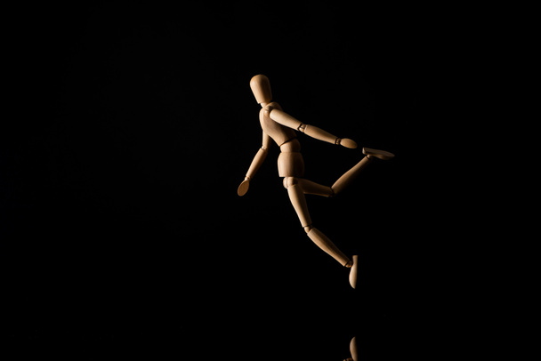 Houten pop in vallende positie op zwart  - Foto, afbeelding