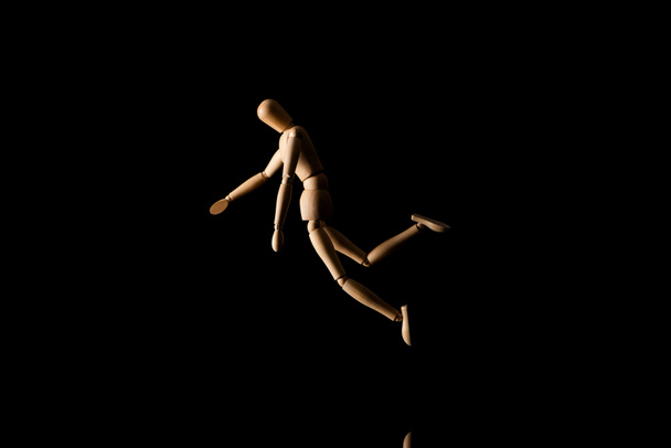 Wooden puppet in falling position on black  - Photo, Image