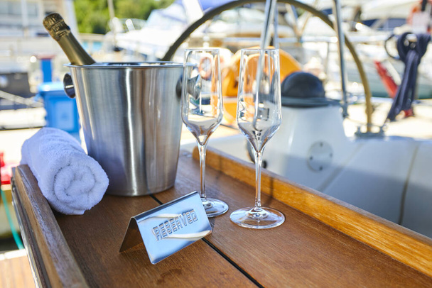 Romantic luxury evening on cruise yacht with champagne setting. Empty glasses and bottle with champagne and tropical sunset with sea background - Photo, Image