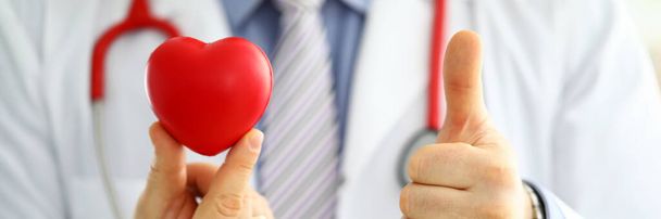 Médico masculino en espera corazón de juguete rojo y mostrar OK
 - Foto, imagen