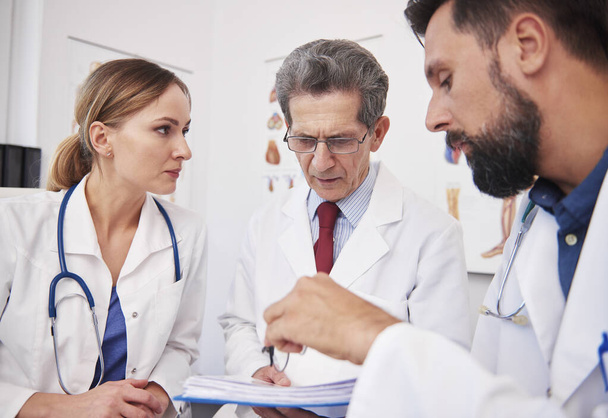 Tre medici che discutono le cartelle cliniche nello studio medico
  - Foto, immagini