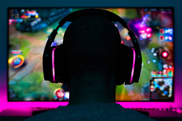 Archivbild eines Spielers mit Kopfhörern bei einem Videospiel vor dem Fernseher - Foto, Bild
