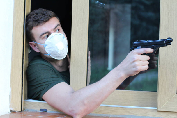 Hombre con máscara protectora sosteniendo un arma
 - Foto, Imagen