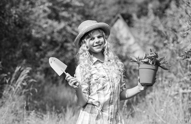 Happy childrens day. Happy childhood. Child in hat with shoulder blade small shovel hoe. Happy smiling gardener girl. Ranch girl. Planting plants. Little kid hold flower pot. Spring country works - Photo, Image