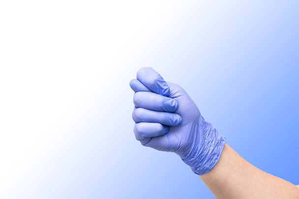 Инжир как жест рукой, обозначающий унижение или отрицание. Мужская рука в фиолетовой латексной перчатке на синем градиентном фоне
. - Фото, изображение
