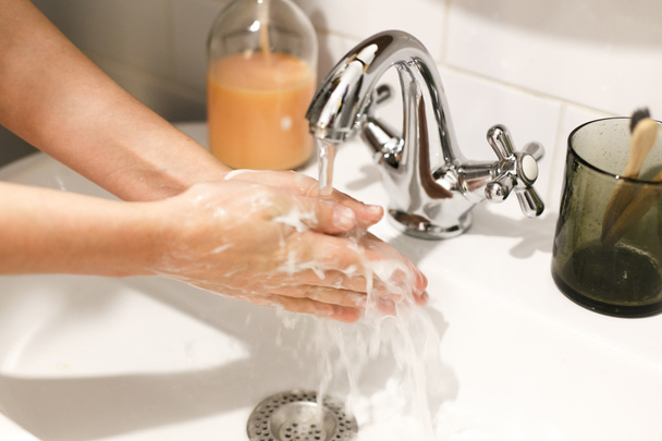 El yıkama. Eller akan suyun altında düzgün bir teknik ve banyoda antibakteriyel sabunla yıkanır. Koronavirüs salgınını önle. Grip hastalığının önlenmesi. - Fotoğraf, Görsel