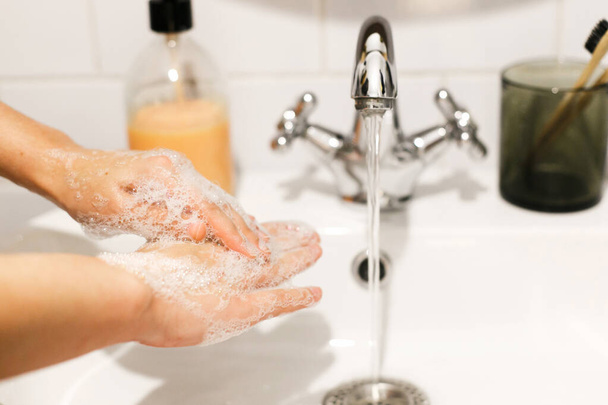 Kézmosás. Kézmosás megfelelő technikával és antibakteriális szappannal a fürdőszobában folyó víz hátterén. Dörzsölöm az ujjaimat. Koronavírus járvány megelőzése. Influenzajárvány megelőzése. - Fotó, kép