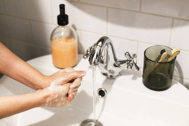 Washing hands. Hands washing with soap foam on background of flowing water in bathroom. Rubbing palms. Prevention of flu disease. Personal hygiene. Cleaning hands to prevent coronavirus epidemic - Фото, изображение