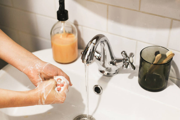 Washing hands. Hands washing with soap foam on background of flowing water in bathroom. Rubbing palms. Prevention of flu disease. Personal hygiene. Cleaning hands to prevent coronavirus epidemic - Photo, Image