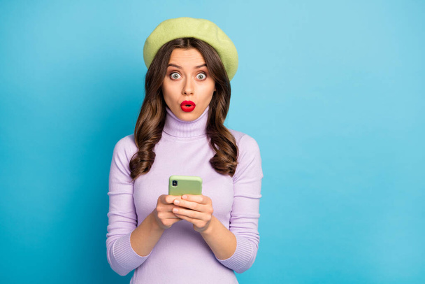 Portrait of astonished girl use cellphone read social network information impressed stare stupor wear lilac color clothing jumper isolated over blue color background - Foto, immagini