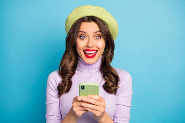 Amazed positive funky girl use smart phone read social media news impressed scream wow omg wear girlish style trendy violet outfit headwear isolated over blue color background - Foto, imagen