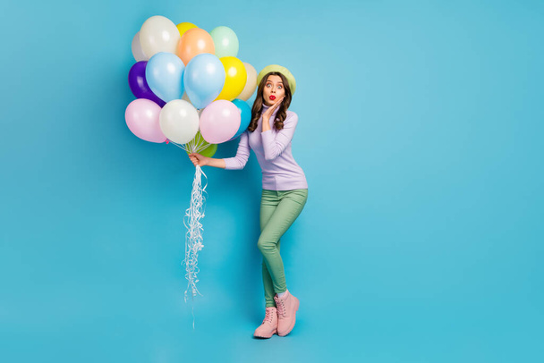 Wow. Full length photo of pretty lady hold colorful air balloons friends surprise event party wear purple pullover beret cap green pants footwear isolated blue color background - Фото, зображення