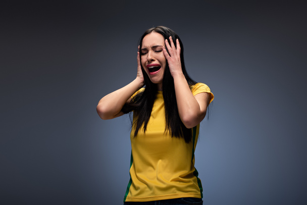 напружена приваблива молода жінка плаче і тримає голову на сірому
 - Фото, зображення